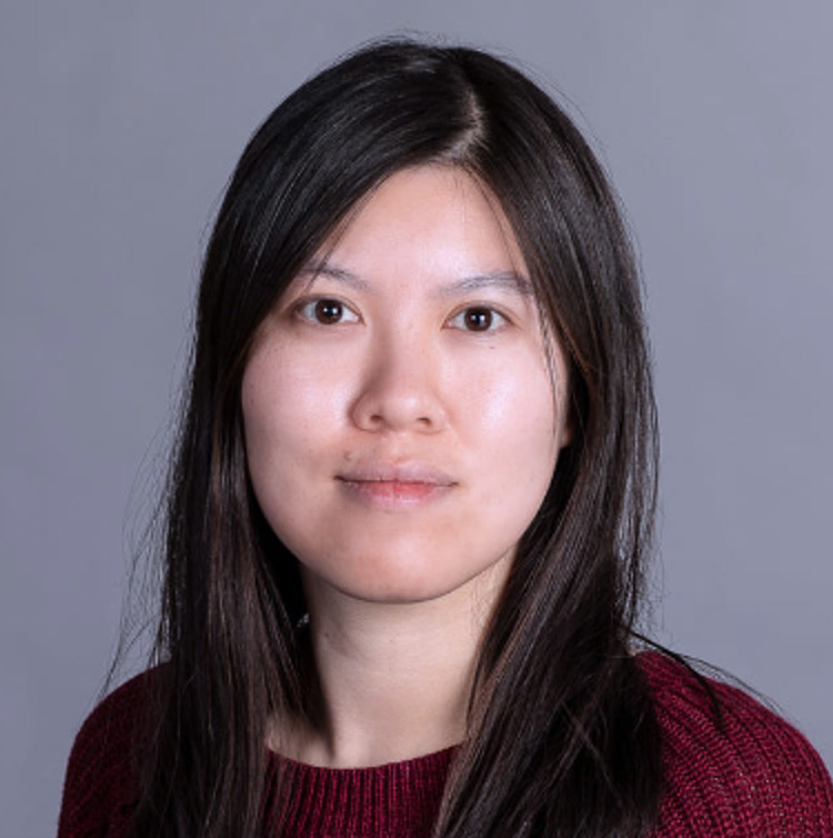 Young Asian woman with dark hair and eyes, wearing a dark red sweater against a gray background.