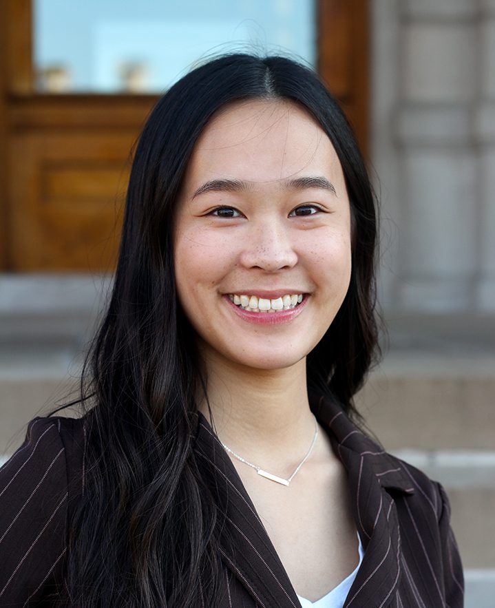 Professional photo of an Asian college student in front of Jesse Hall, with long dark hair and wearing a dark brown pinstriped suit.