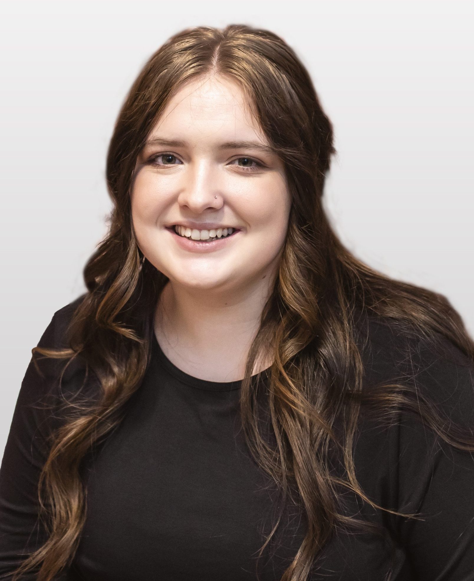College student with fair skin and dark brown curled hair. She is smiling. She wears a black plain shirt.